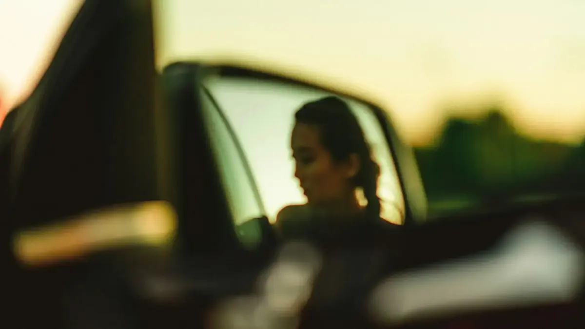 a woman is seen in the side view mirror of a car