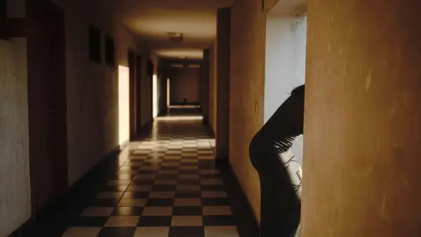 A person peeking around a corner in a hallway