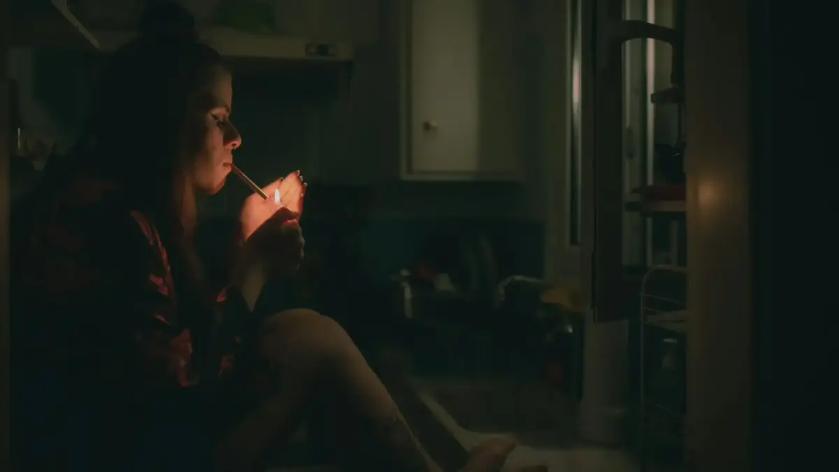 a woman sitting on a kitchen counter smoking a cigarette