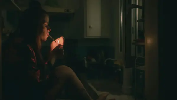 a woman sitting on a kitchen counter smoking a cigarette