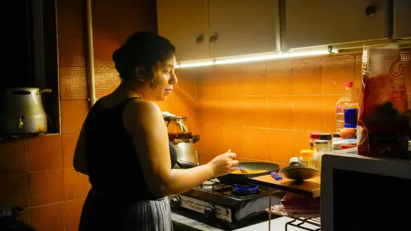 A woman cooks food in a small kitchen.