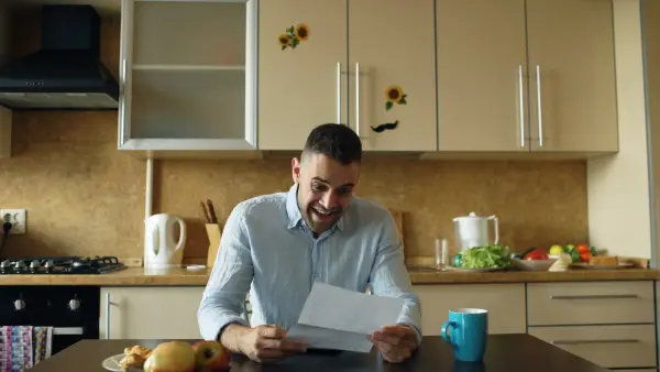 Man reading a letter at a kitchen table