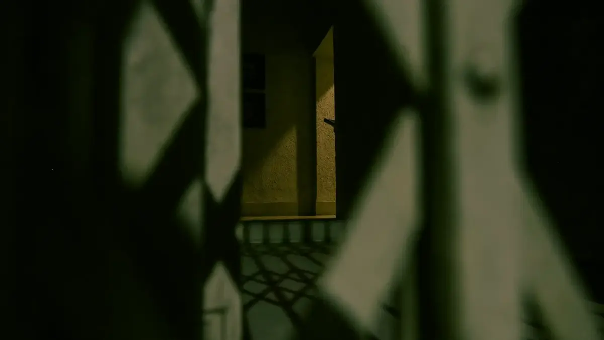 Shadows cast through a decorative gate at night.