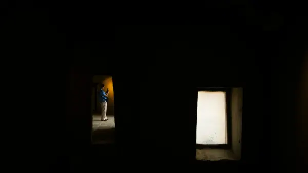 A person stands in a dark room.