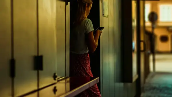 A woman is texting while standing indoors.
