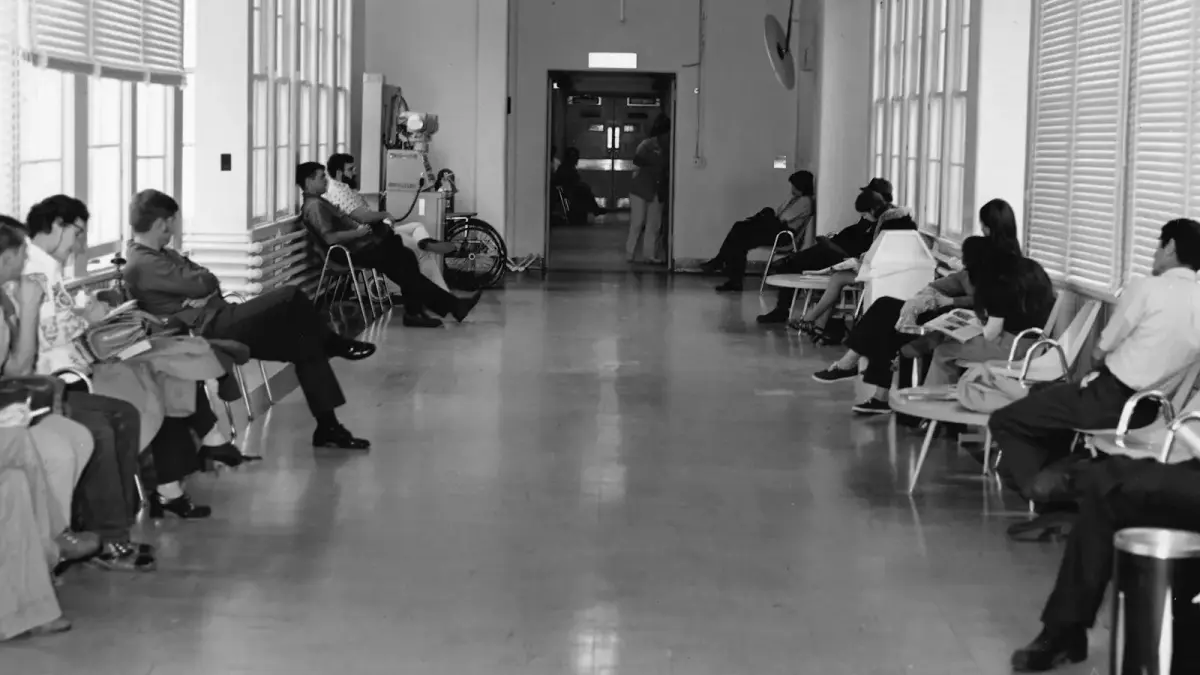 People waiting in a hallway with chairs and chairs