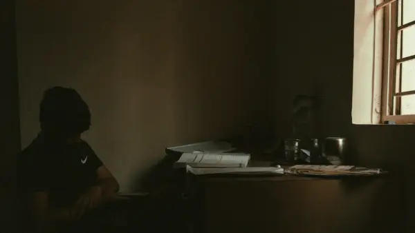 a woman sitting in a dark room next to a window