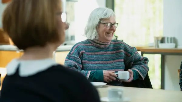 a woman sitting at a table with a cup of coffee
