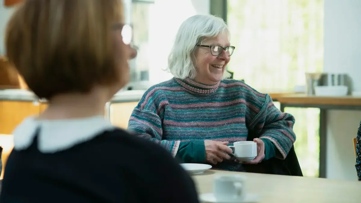 a woman sitting at a table with a cup of coffee