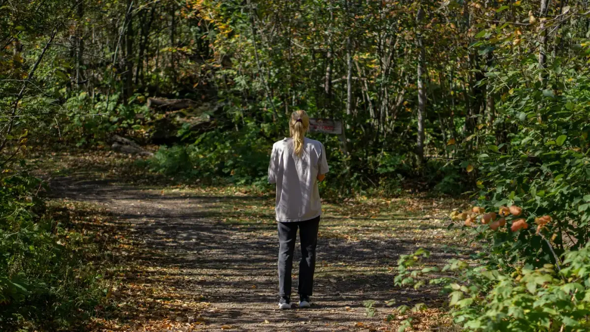 Woman walking on a path through an autumn forest.