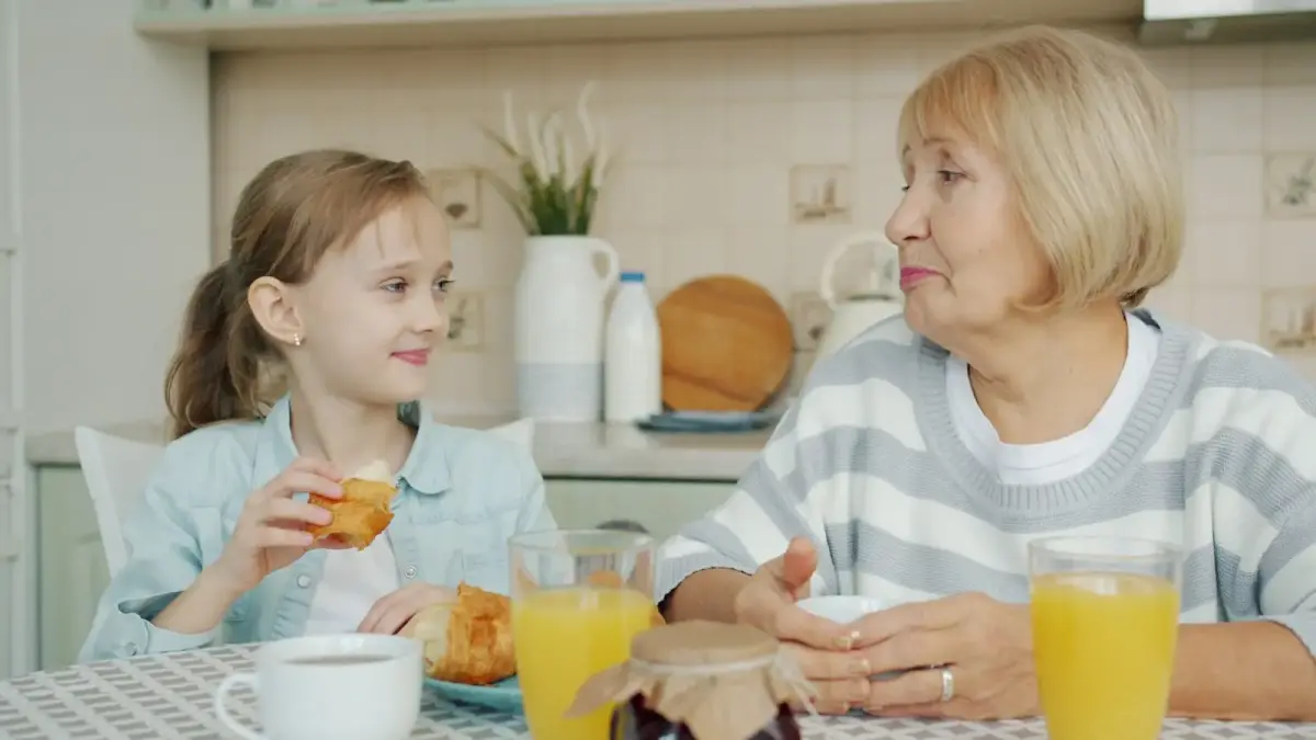 Grandmother and granddaughter sharing breakfast at table.