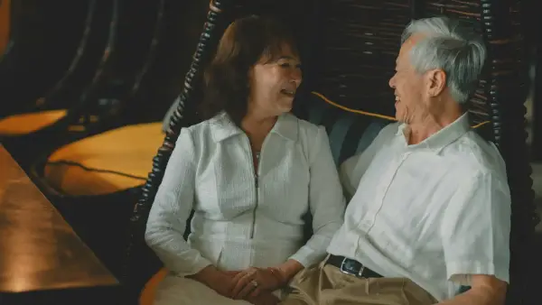 Elderly couple holding hands and smiling at each other.