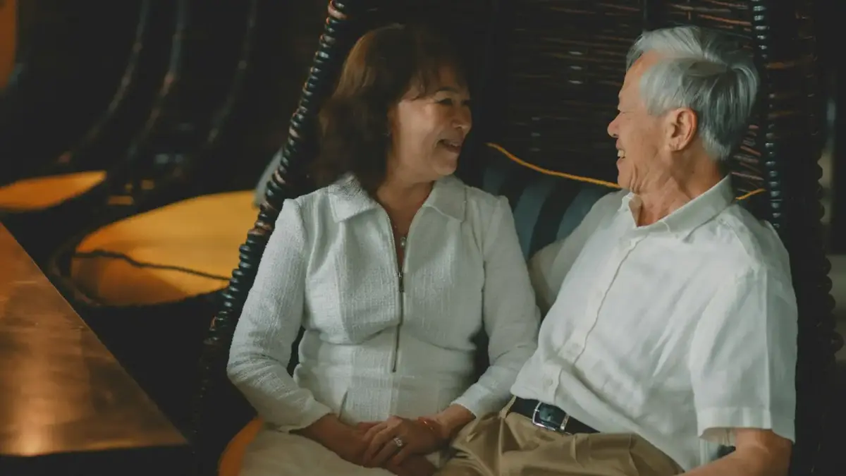 Elderly couple holding hands and smiling at each other.