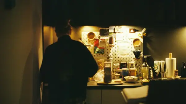 a man standing in a kitchen next to a refrigerator