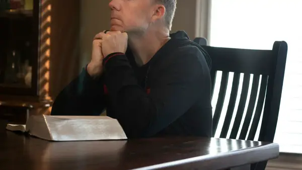 a man sitting at a table with his hands folded