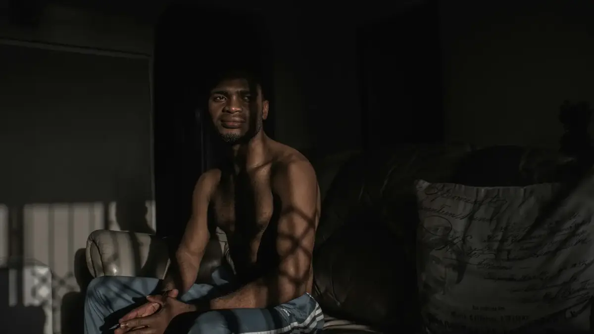 topless man sitting on black and white textile