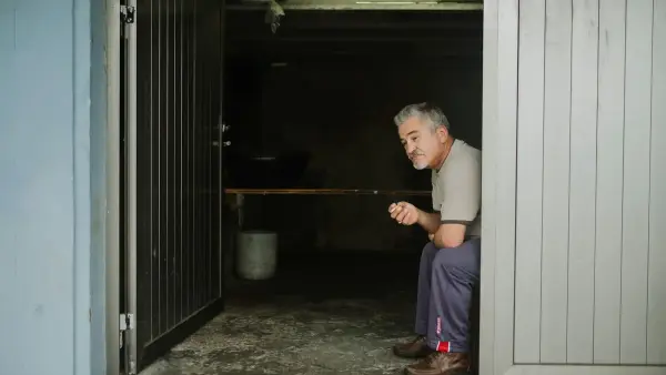 man in white long sleeve shirt and blue pants standing beside door
