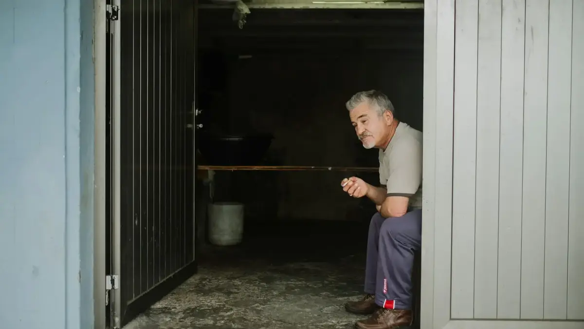 man in white long sleeve shirt and blue pants standing beside door