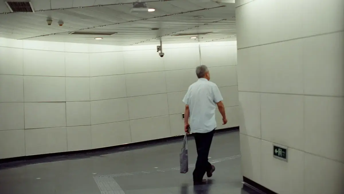 Man walking down a modern, brightly lit hallway.