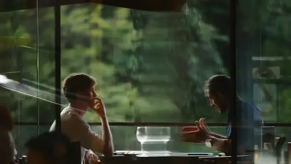 Two people talking at a table by a window