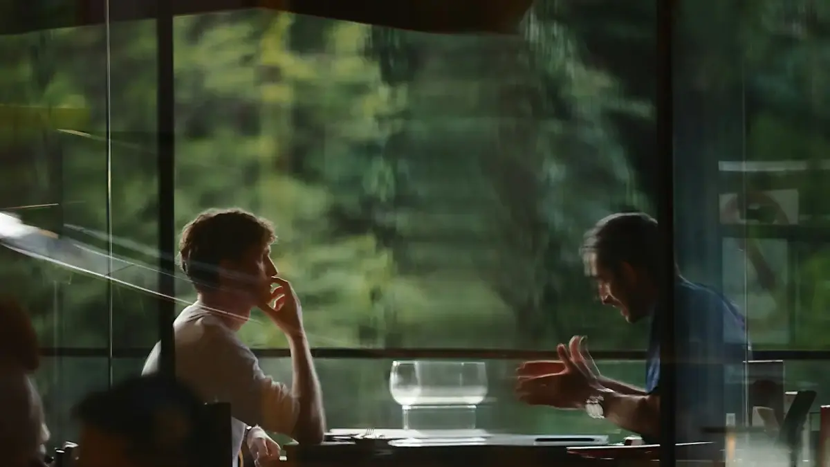 Two people talking at a table by a window