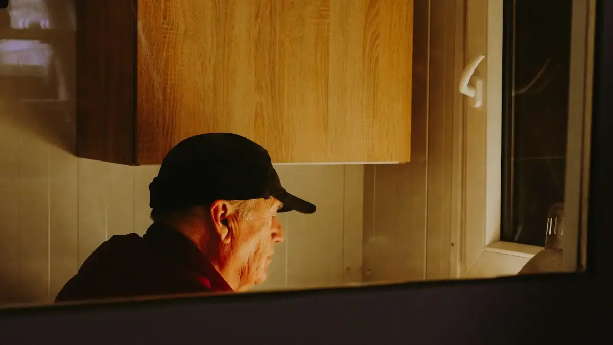a man wearing a hat looking in a mirror