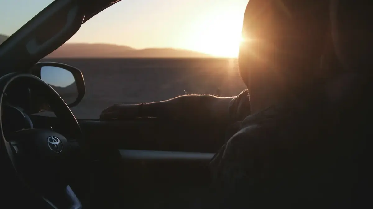 silhouette of man riding in Toyota car looking at sunset