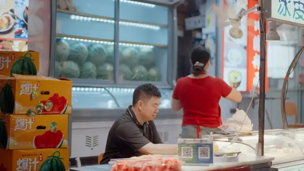 Man sits at a fruit stand with watermelons