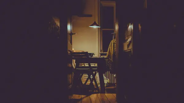 A man checking a door lock in the warm hallway light of his home before bed