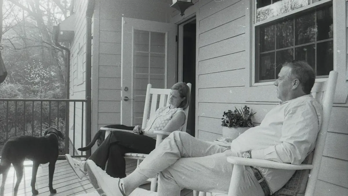 A couple and their dog relaxing on a porch.
