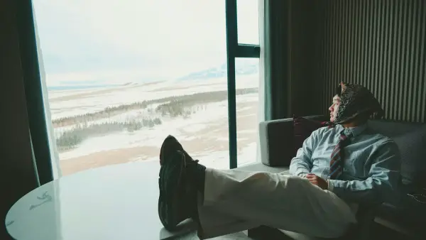 Man in suit looking out window at snowy landscape