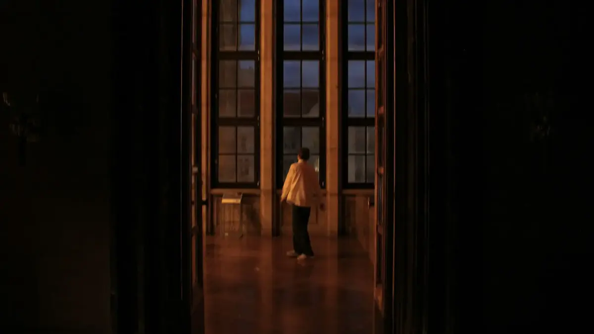 Person stands in grand room with large windows
