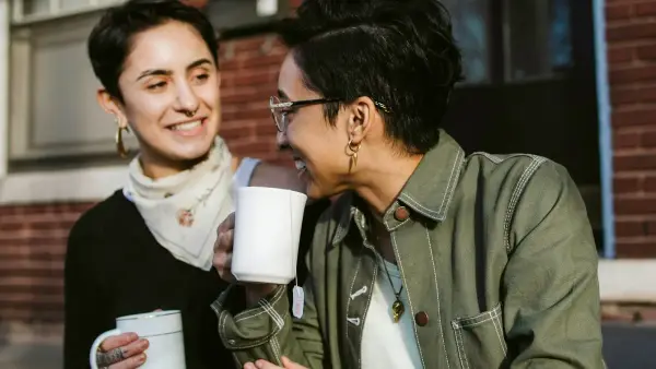 woman in brown jacket holding white ceramic mug