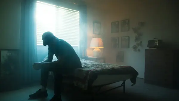 man in black jacket sitting on bed