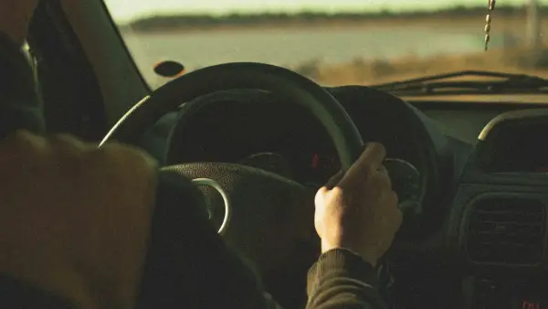 A man behind the wheel on an open road, finding peace in the only silence nobody questions