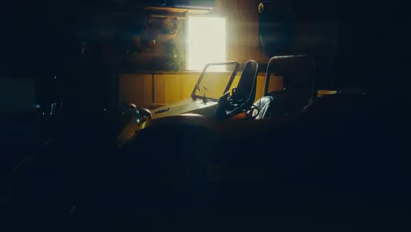 Sunlight illuminates a vehicle in a dark garage.