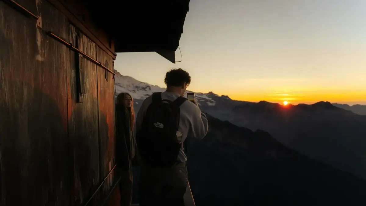 Couple watching sunrise over mountain range from balcony