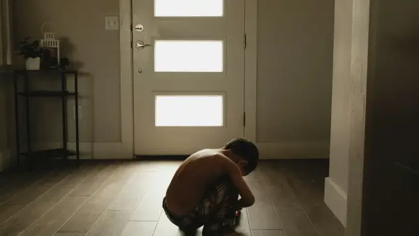 A person kneeling on the floor in front of a door