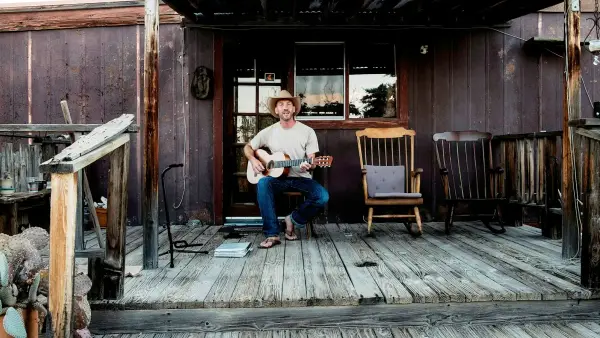 A middle aged man sitting alone on porch steps in quiet morning light