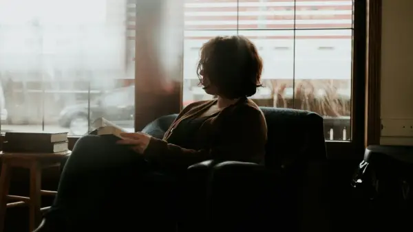 woman in black and brown plaid long sleeve shirt sitting on black sofa