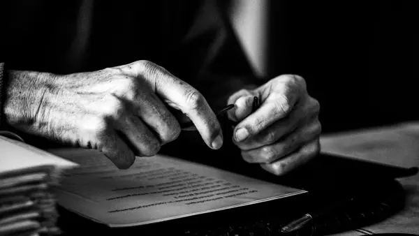 a black and white photo of a person's hands on a book