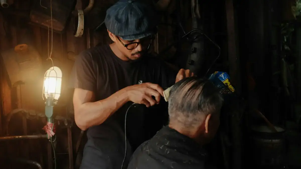 barber clipping the hair of the man