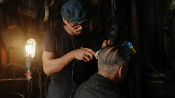 barber clipping the hair of the man