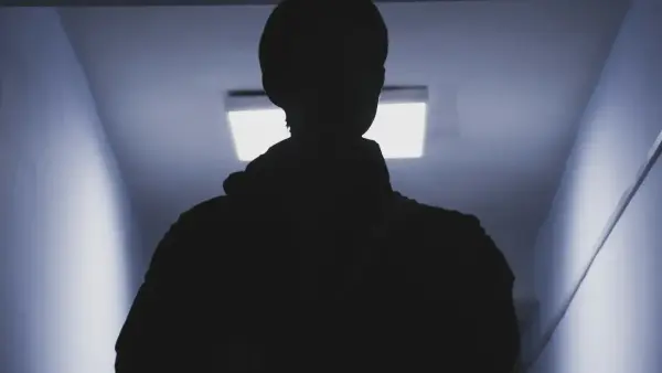 A silhouette of a person standing in a dark hallway