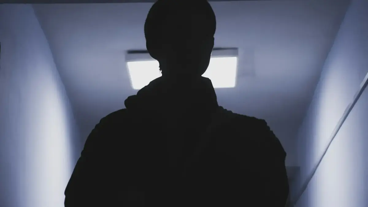 A silhouette of a person standing in a dark hallway