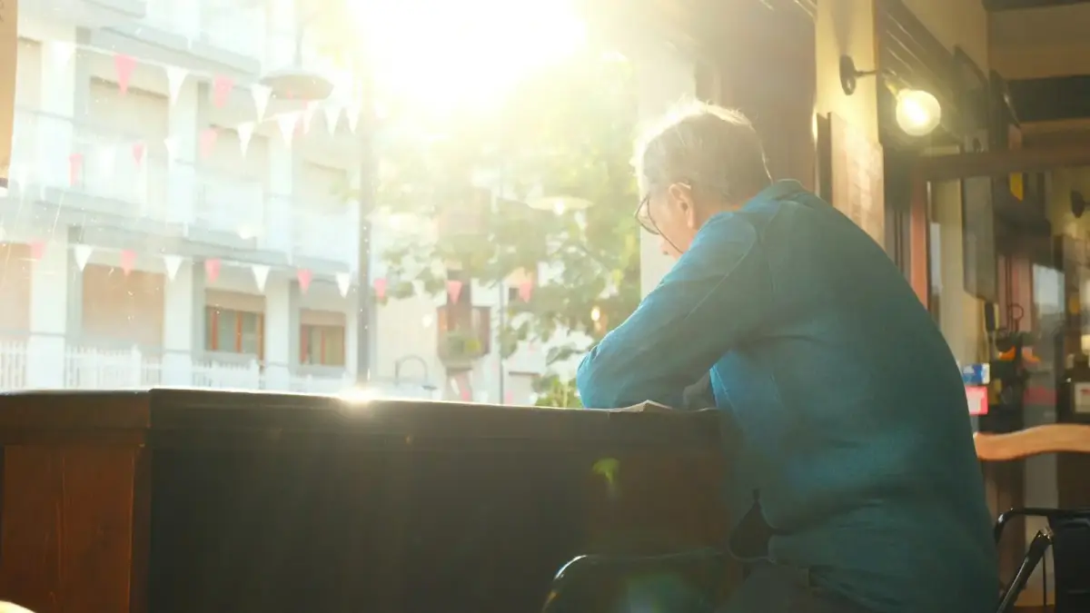 Man looking out a sunlit window indoors