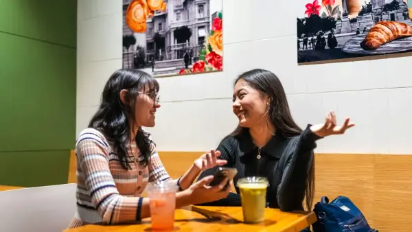 Two young women talking at a cafe table.