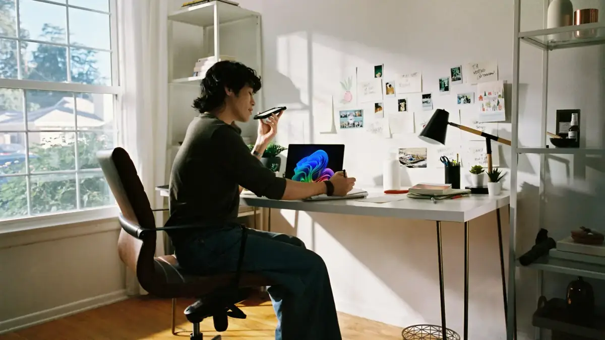 Person working at desk with laptop and phone.