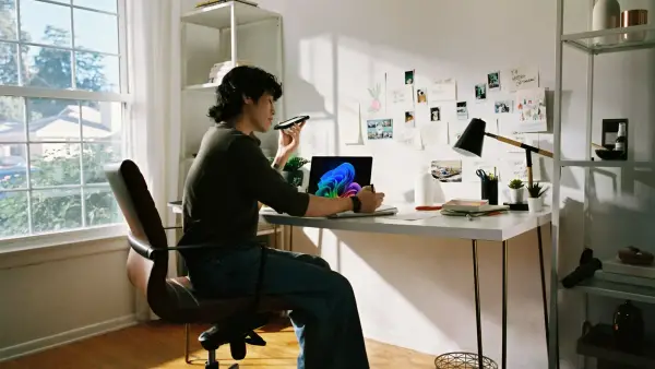 Person working at desk with laptop and phone.