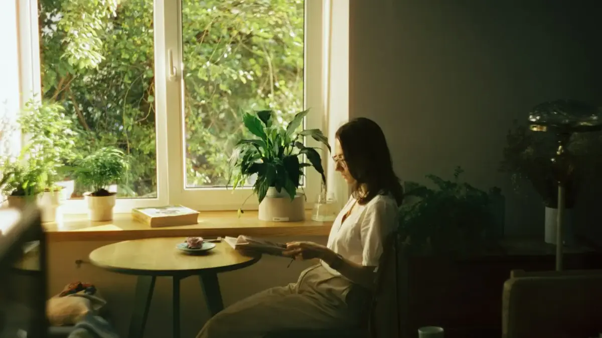 woman in white dress shirt sitting on chair near window during daytime
